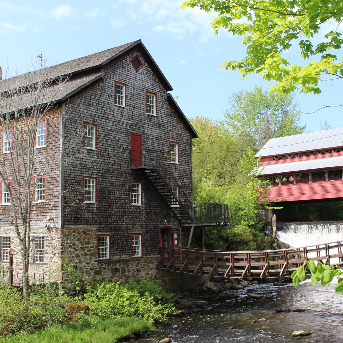 Exterior of the ancestral building, with a small wooden bridge over a stream.