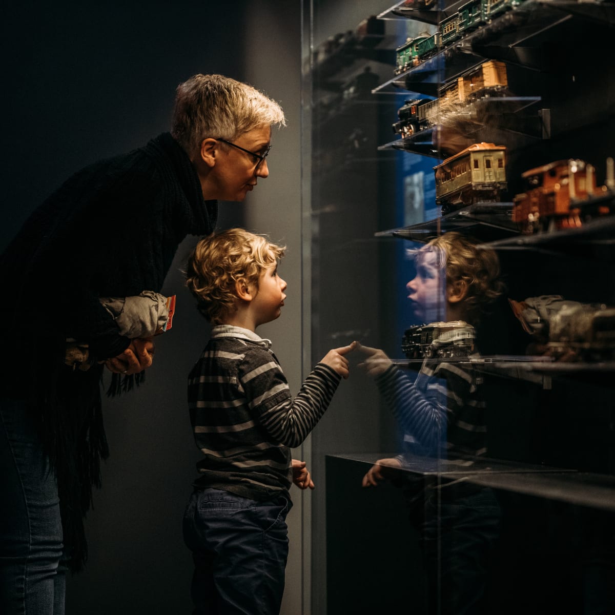 Young boy and grandparent looking at a model train exhibit