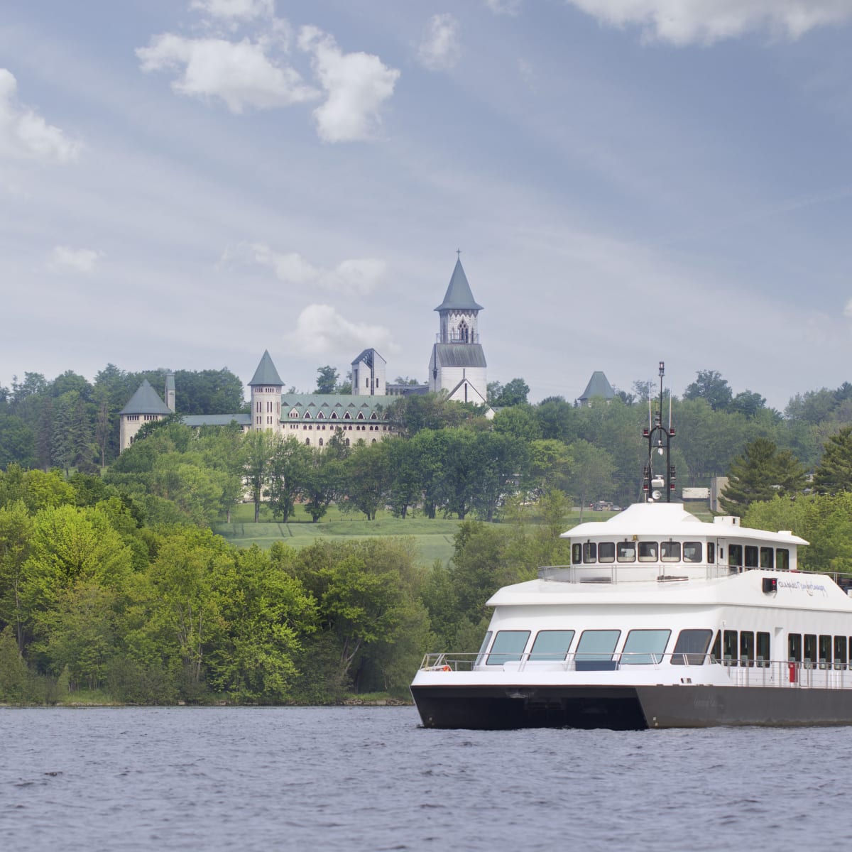 Cruise ship on a lake. There is an abbey in the background.
