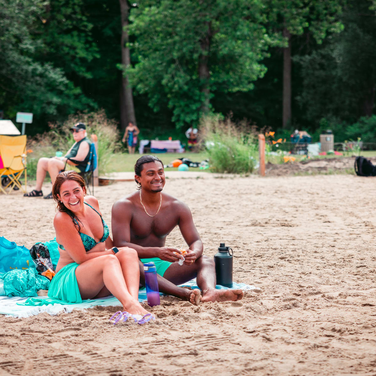 Happy-looking couple sitting on a beach towel.