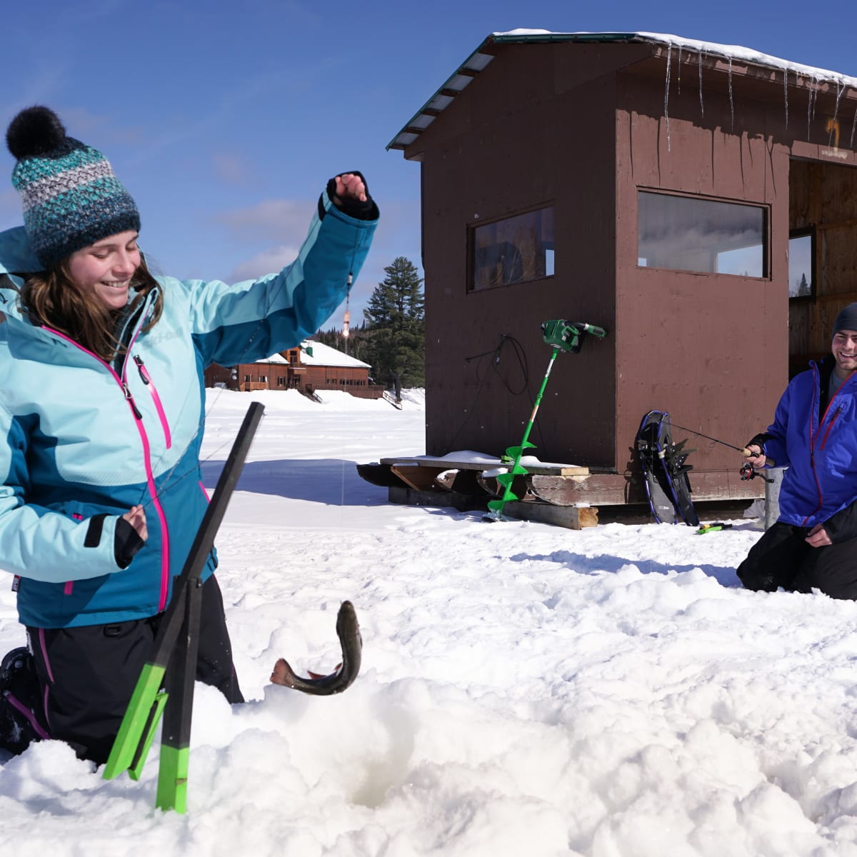 Couple en train de faire de la pêche sur glace par une journée ensoleillée.