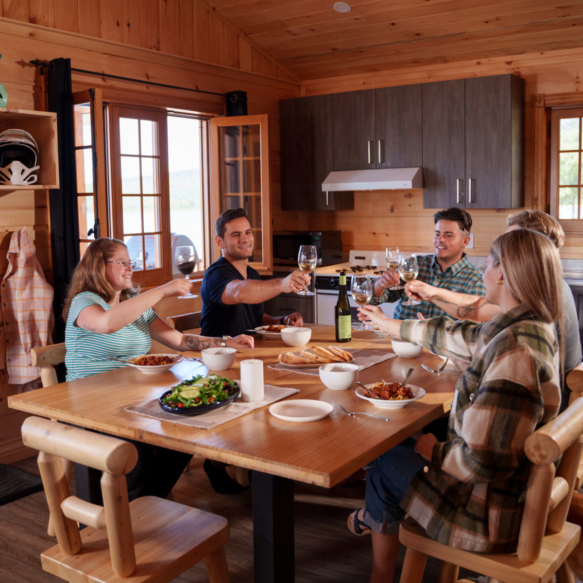 Groupe de convives autour d'une table à l'intérieur d'un chalet en bois.