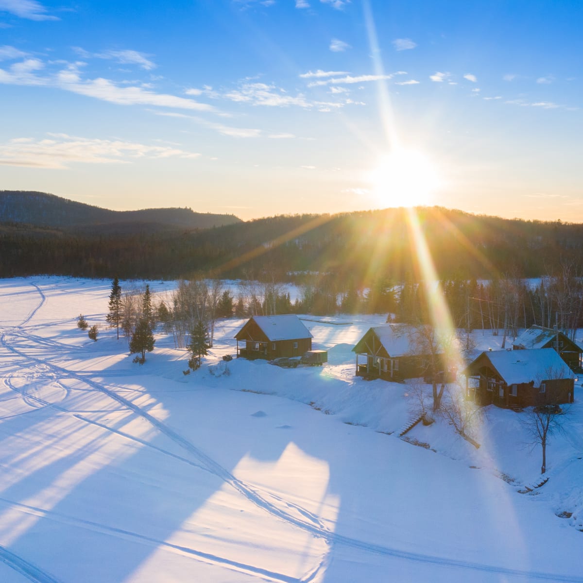 Vue aérienne de chalets sous la neige au bord d’un lac.