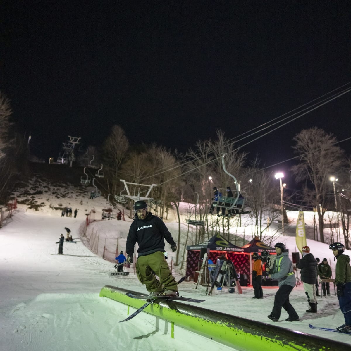 Homme en train de sauter sur un module en planche à neige en soirée.