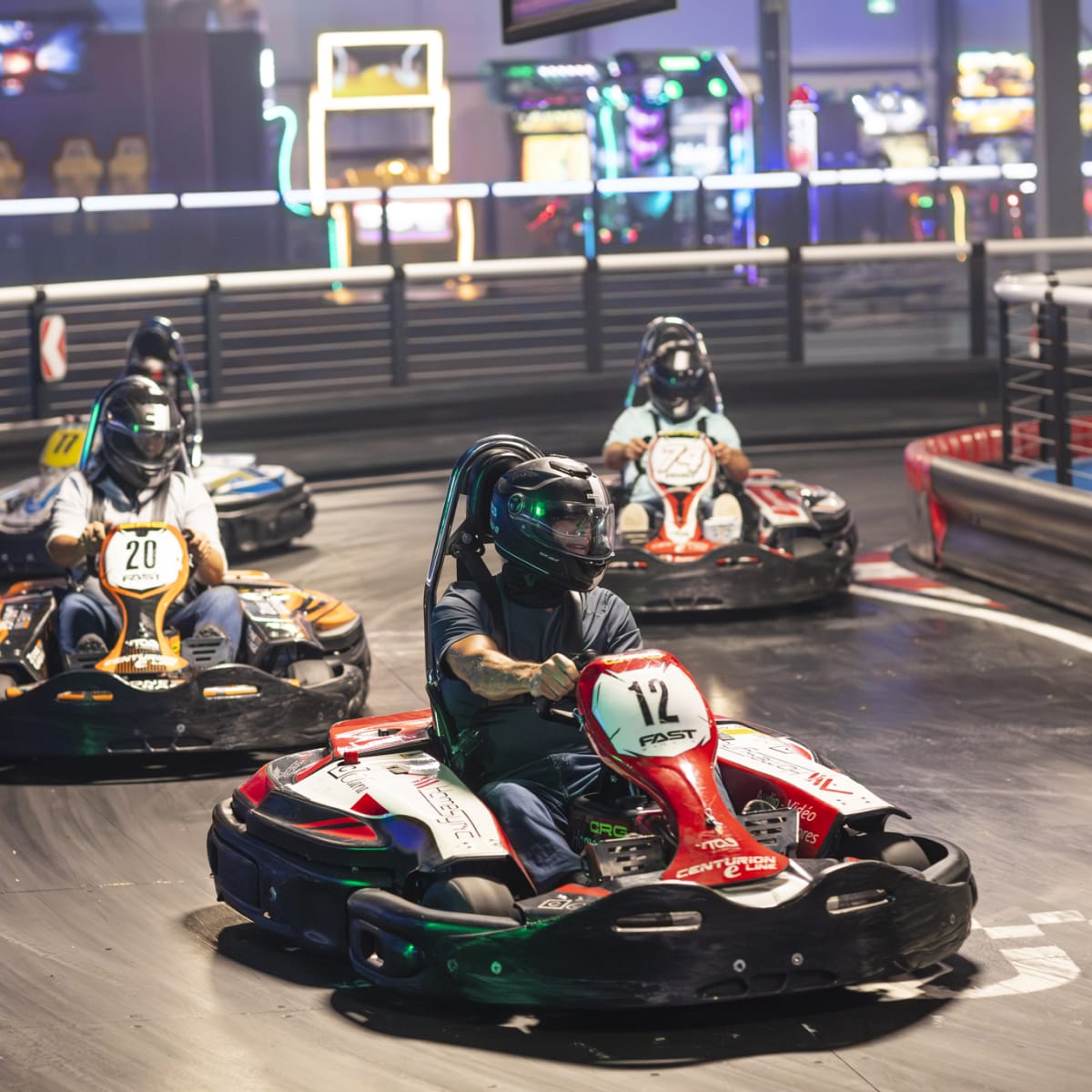 Four people in karts on a racetrack.