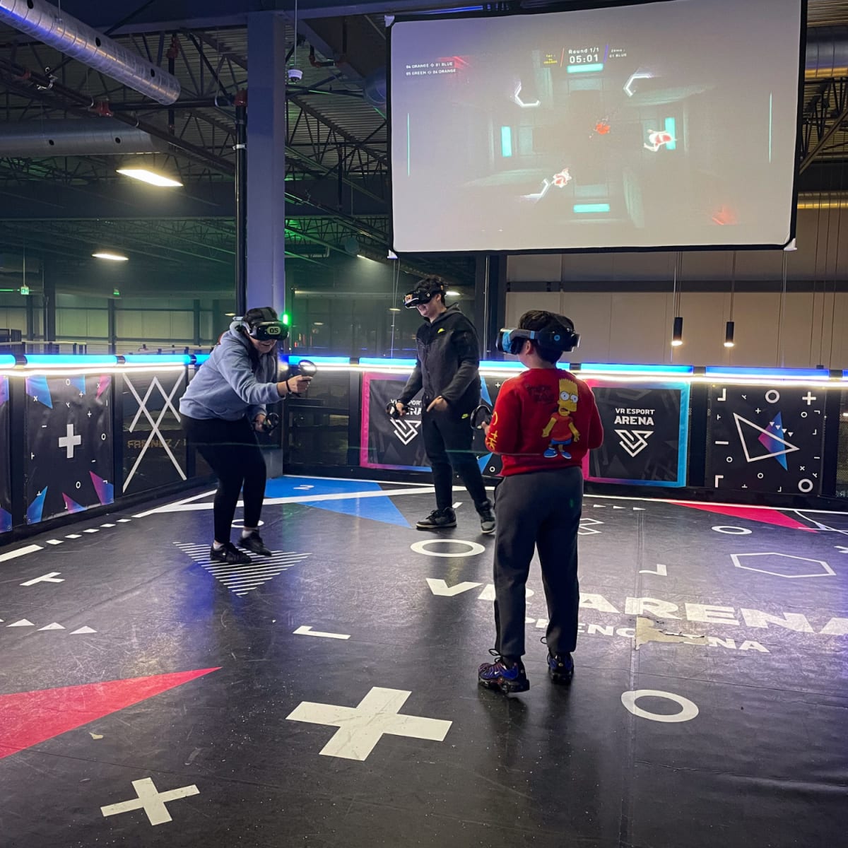 Three people facing off in a virtual reality arena.