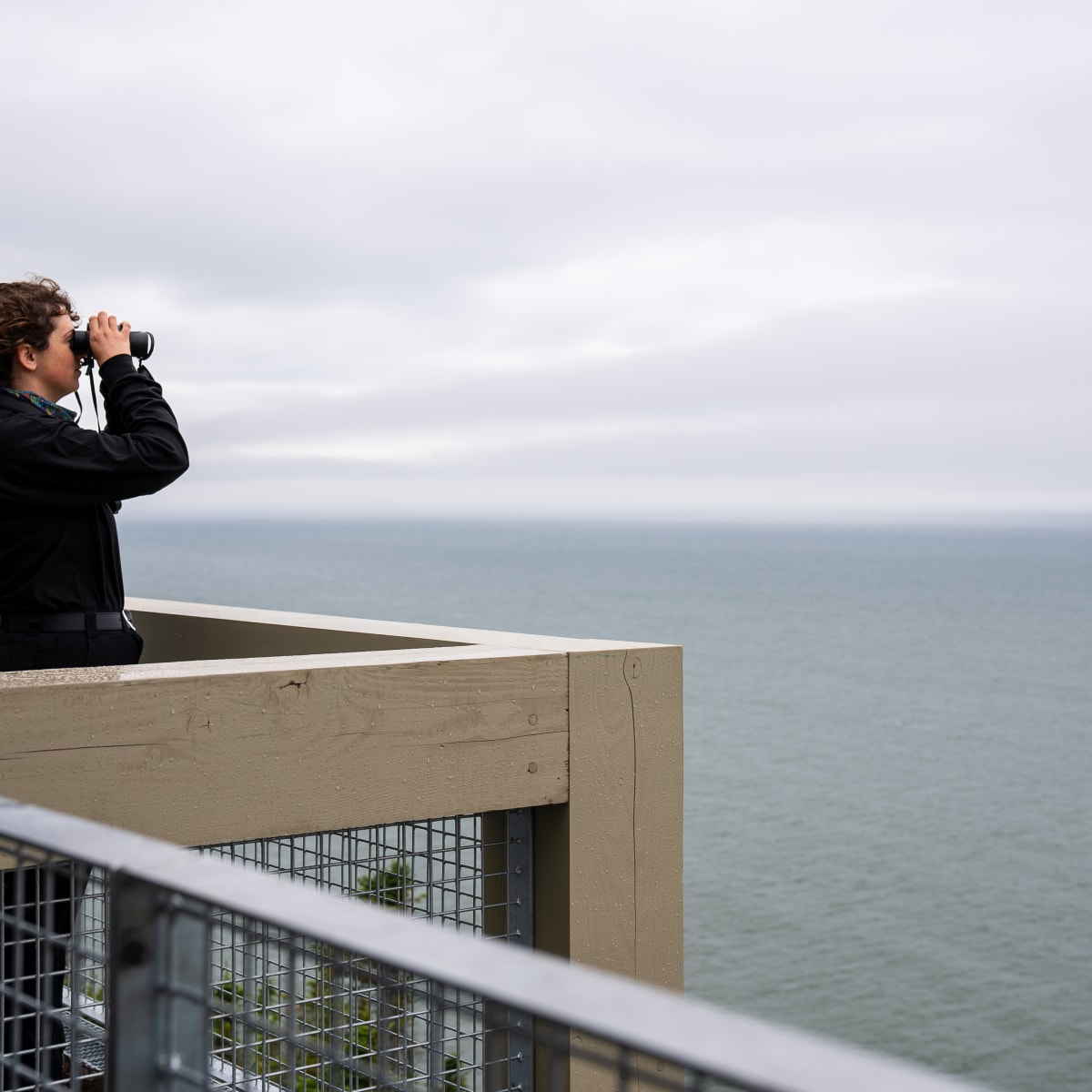 Woman looking at  the sea with binoculars.