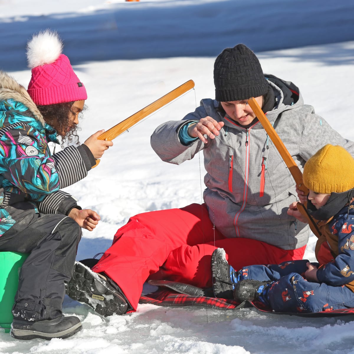 Parent and two kids ice fishing.