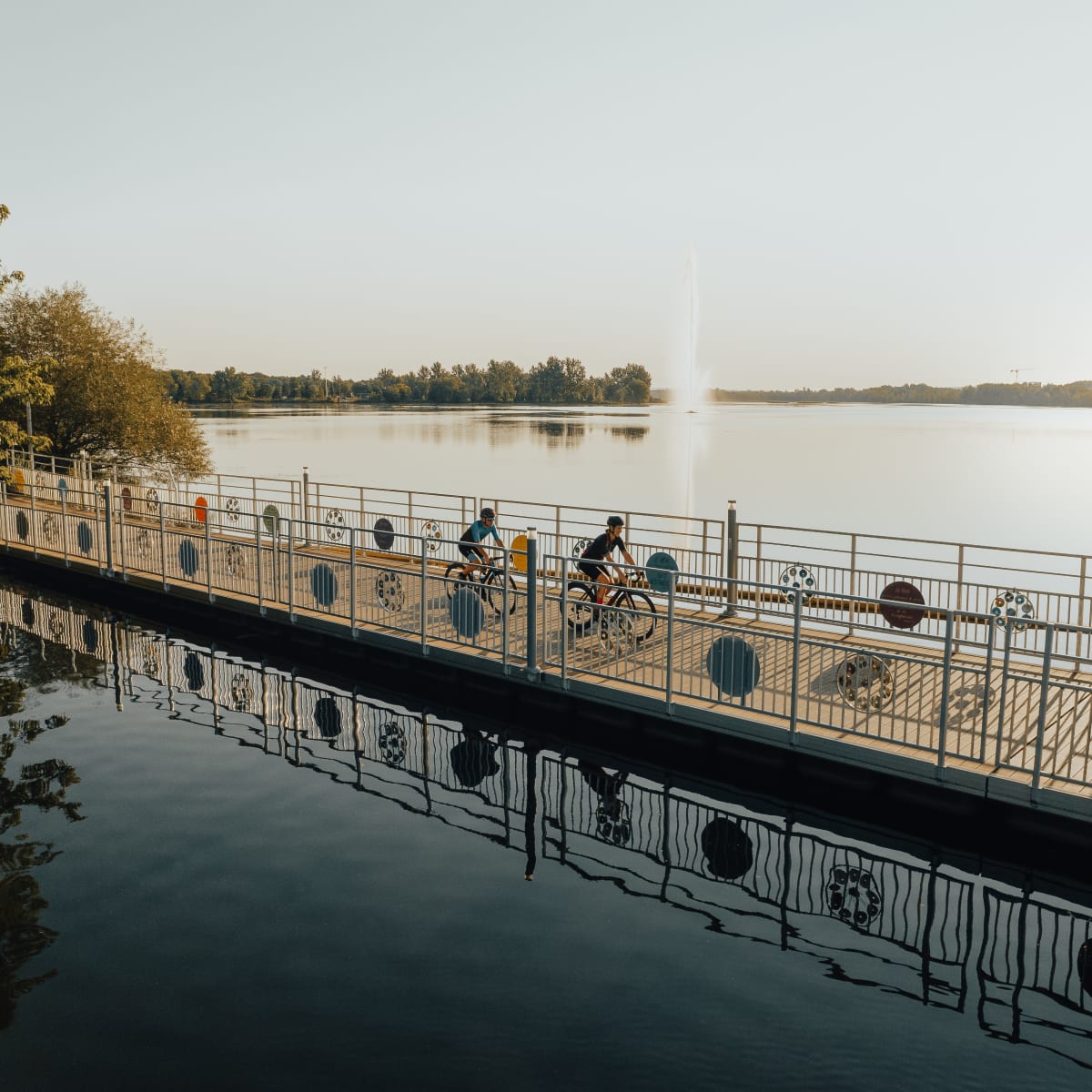 Two cyclists on a bike path over the water.