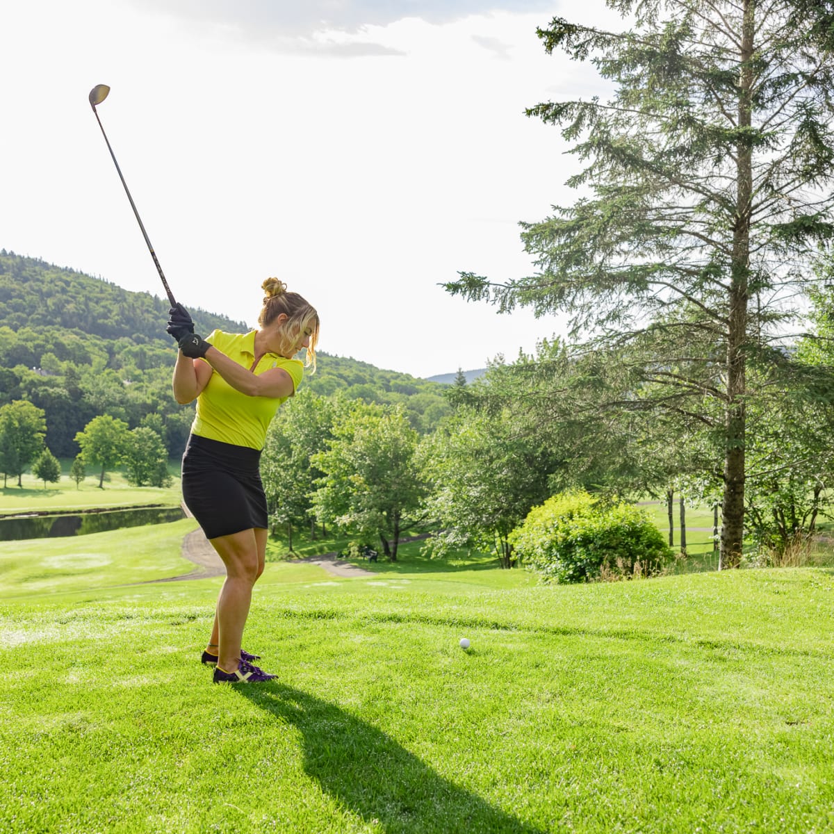 Woman on a golf course about to hit the ball.