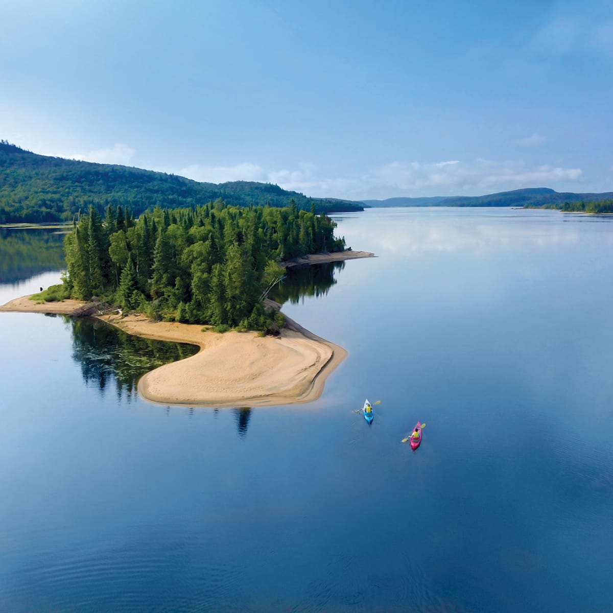 Vue aérienne d’une petite île avec plage au milieu d’un grand lac.
