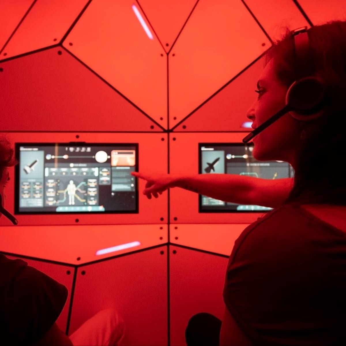 Mother and son wearing headphones sitting in front of screens at the space exhibit.
