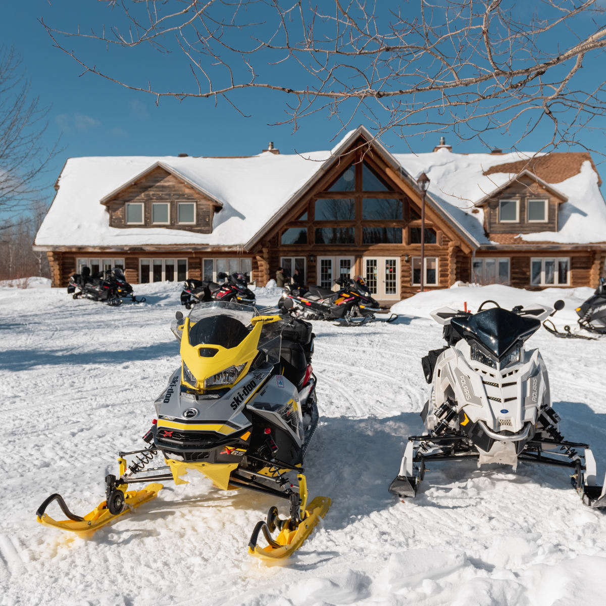 Two snowmobiles in front of a lodge