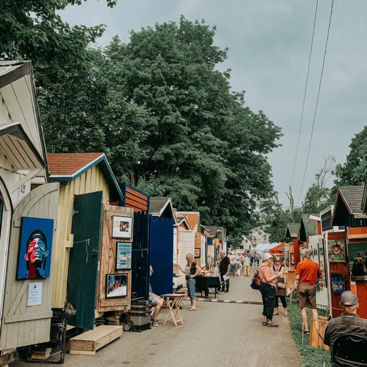 An alleyway lined with small cabins showcasing works of art.