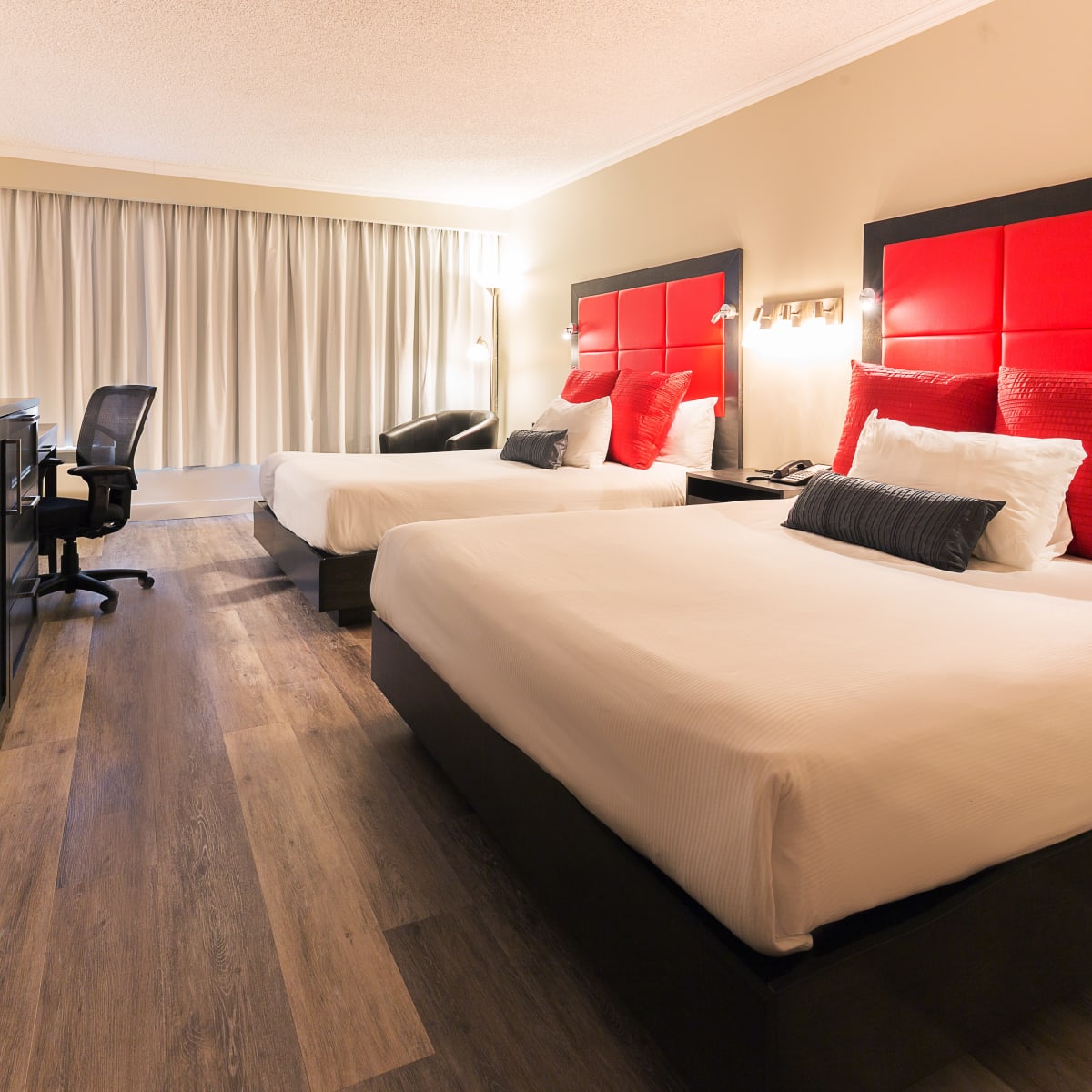 Intérieur d’une chambre d’hôtel aux accents rouges avec deux grands lits