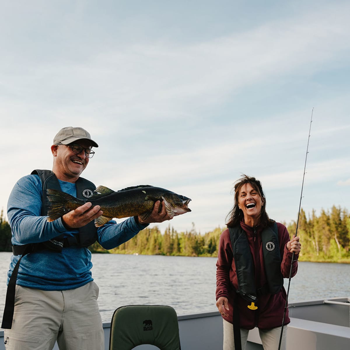 Un homme tient un poisson et une femme tient une canne à pêche, à la Réserve faunique Ashuapmushuan.