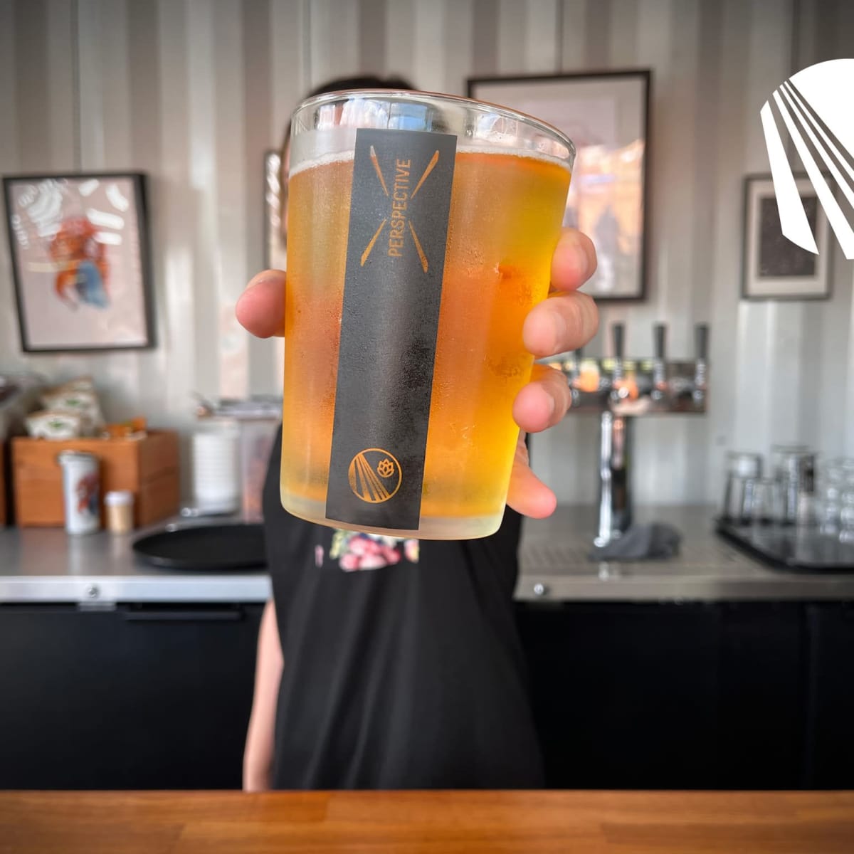 Gros plan sur un verre rempli de bière à l'effigie de la microbrasserie Perspective.