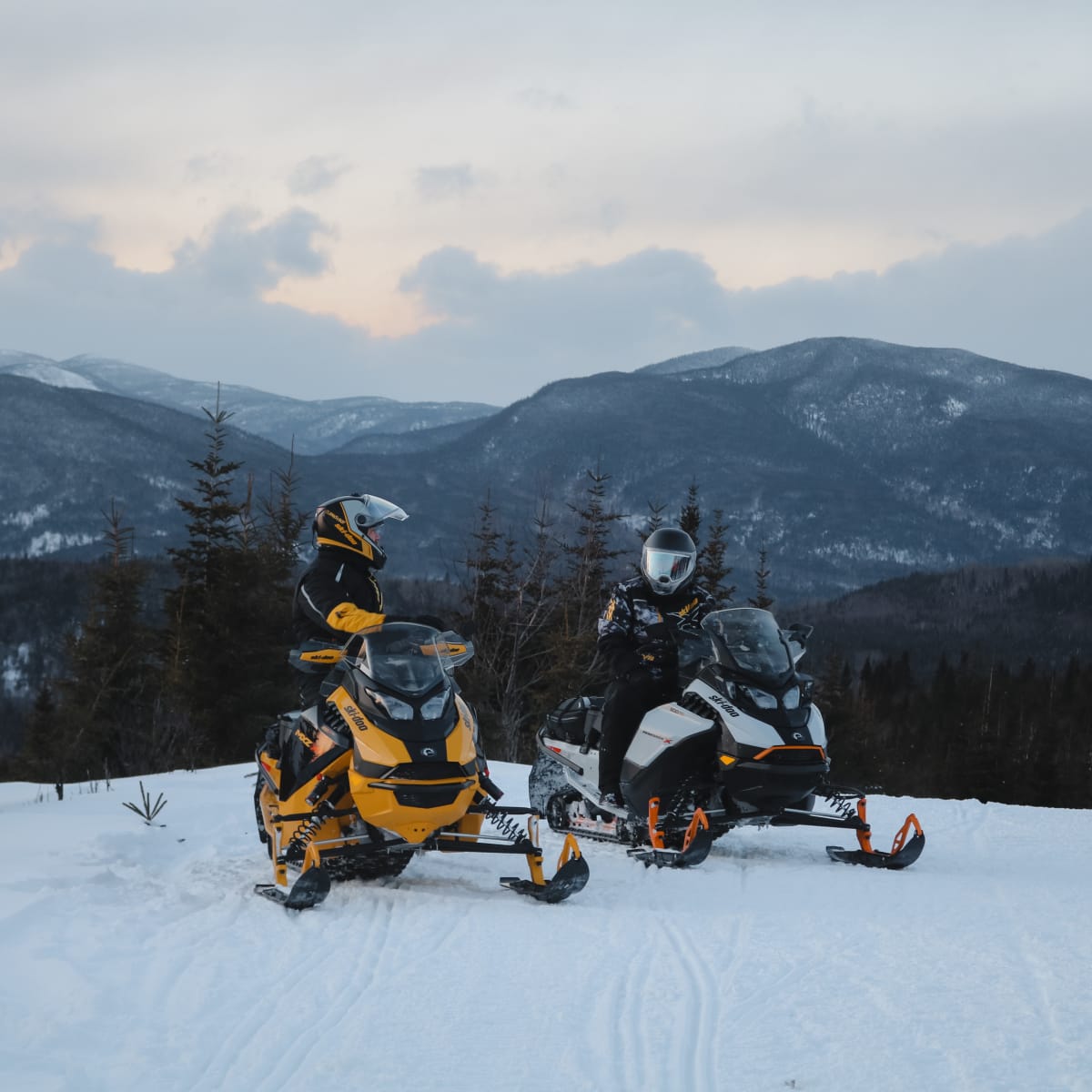Two snowmobilers in the mountains.