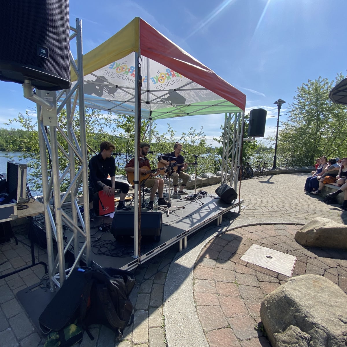 Sherbrooke en musique - Music group performs on an outdoor stage by the water.