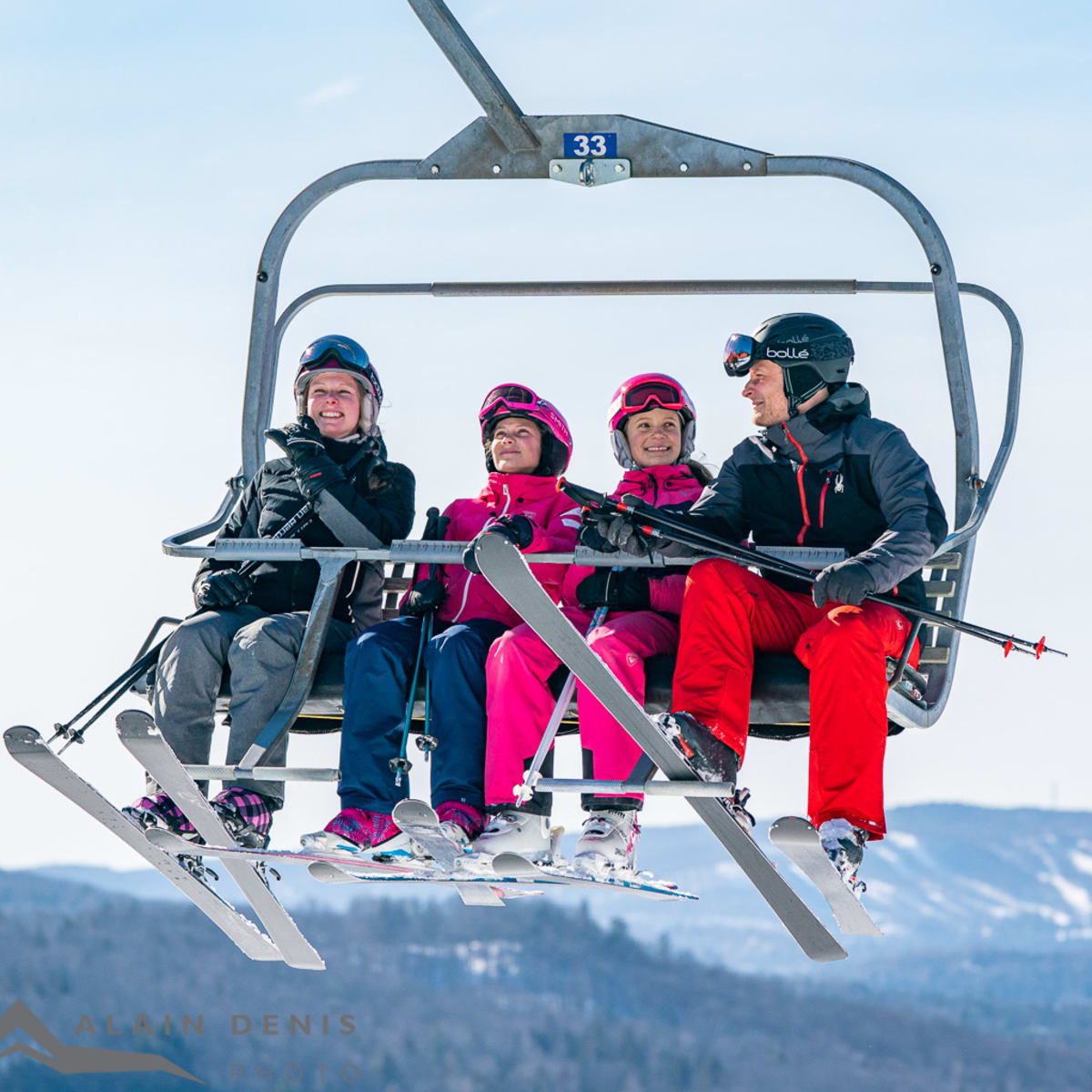 Four skiers on a ski lift at Sommet Olympia.