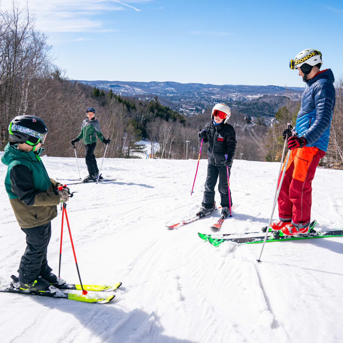 Two adults and two children skiing at Sommet Olympia.