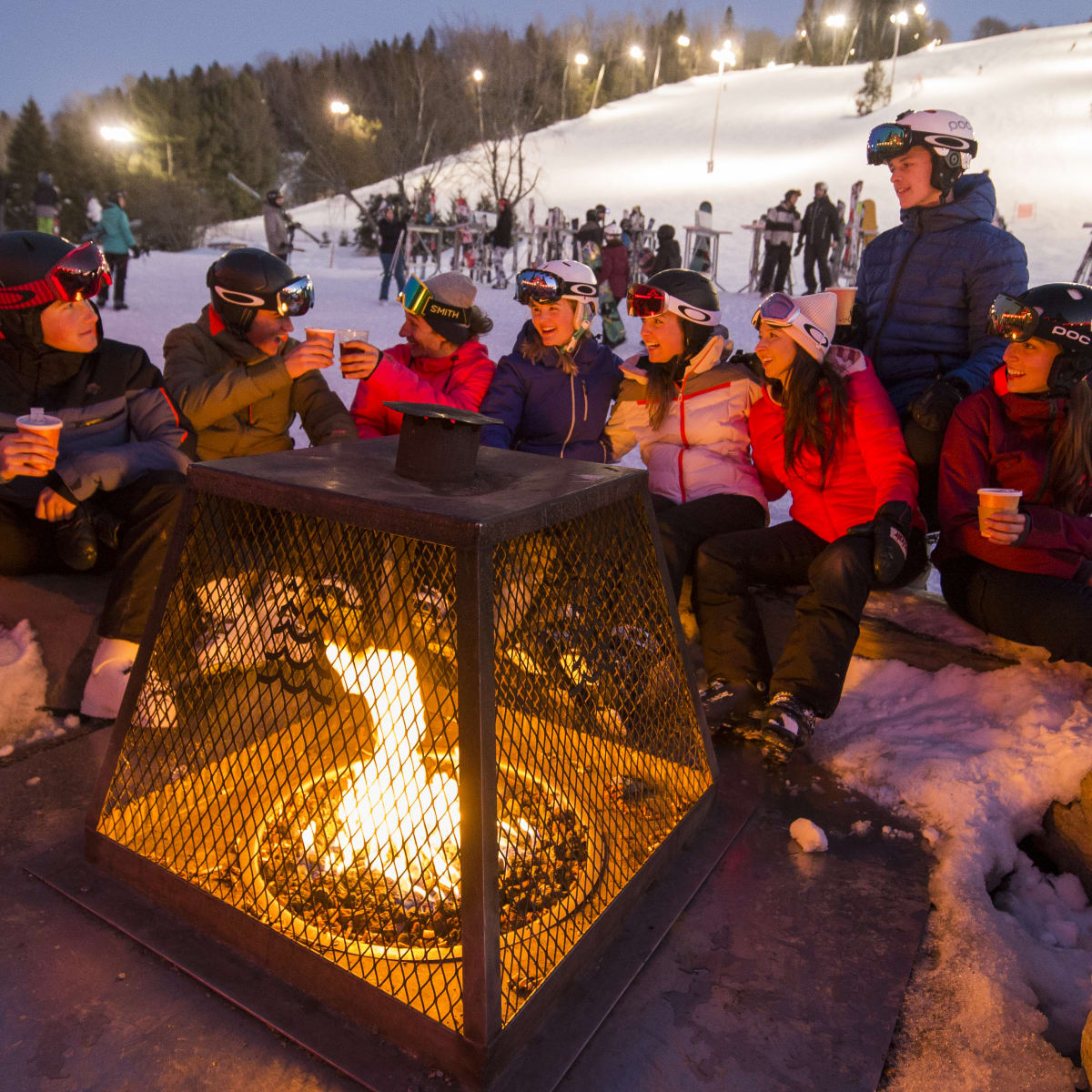 Friends gathered around a fire at the bottom of the Sommet Saint-Sauveur ski mountain.