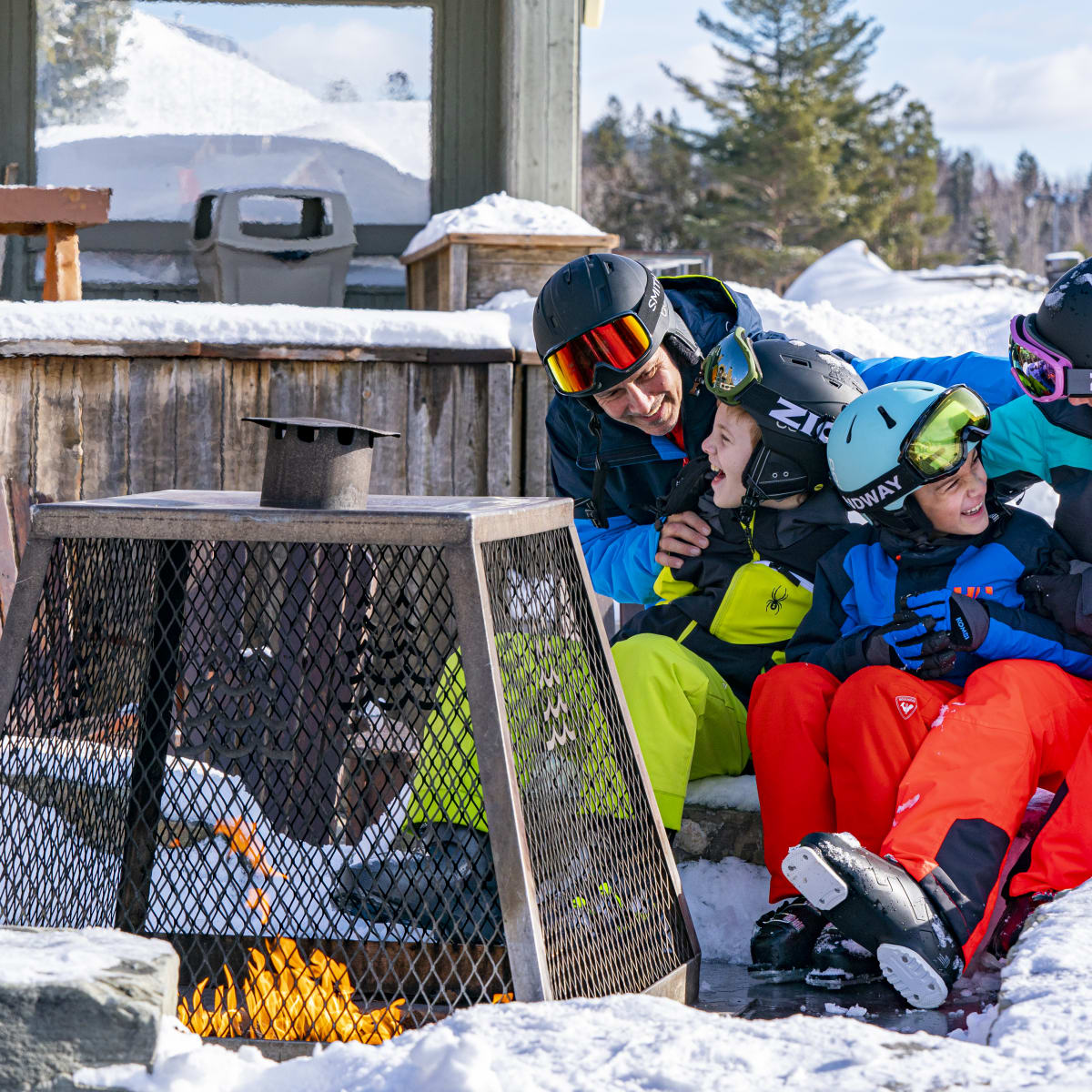 A family gathered around a fire at the bottom of the Sommet Saint-Sauveur ski mountain.