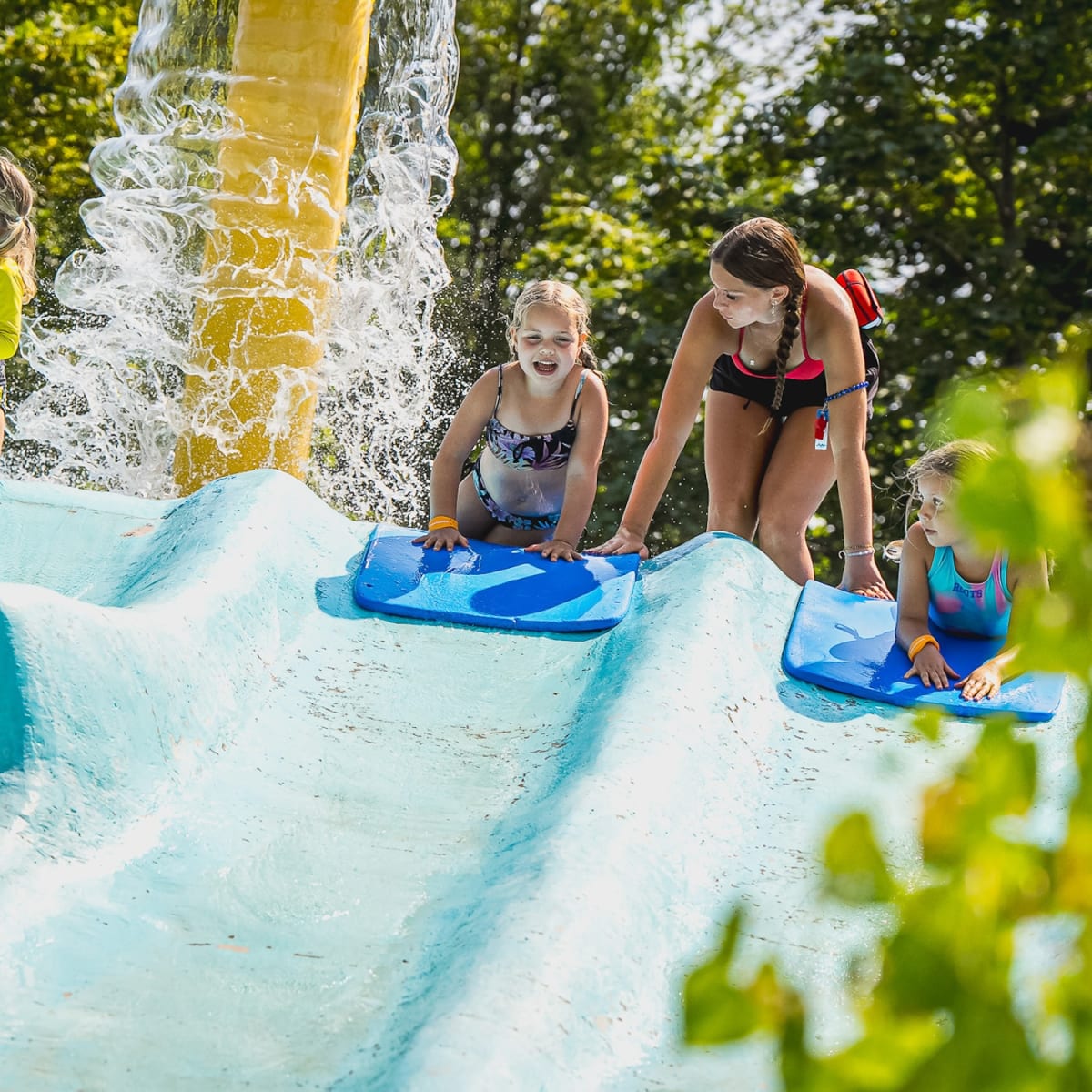 Two young children sliding down a water slide on a mat at the Super Aqua Club