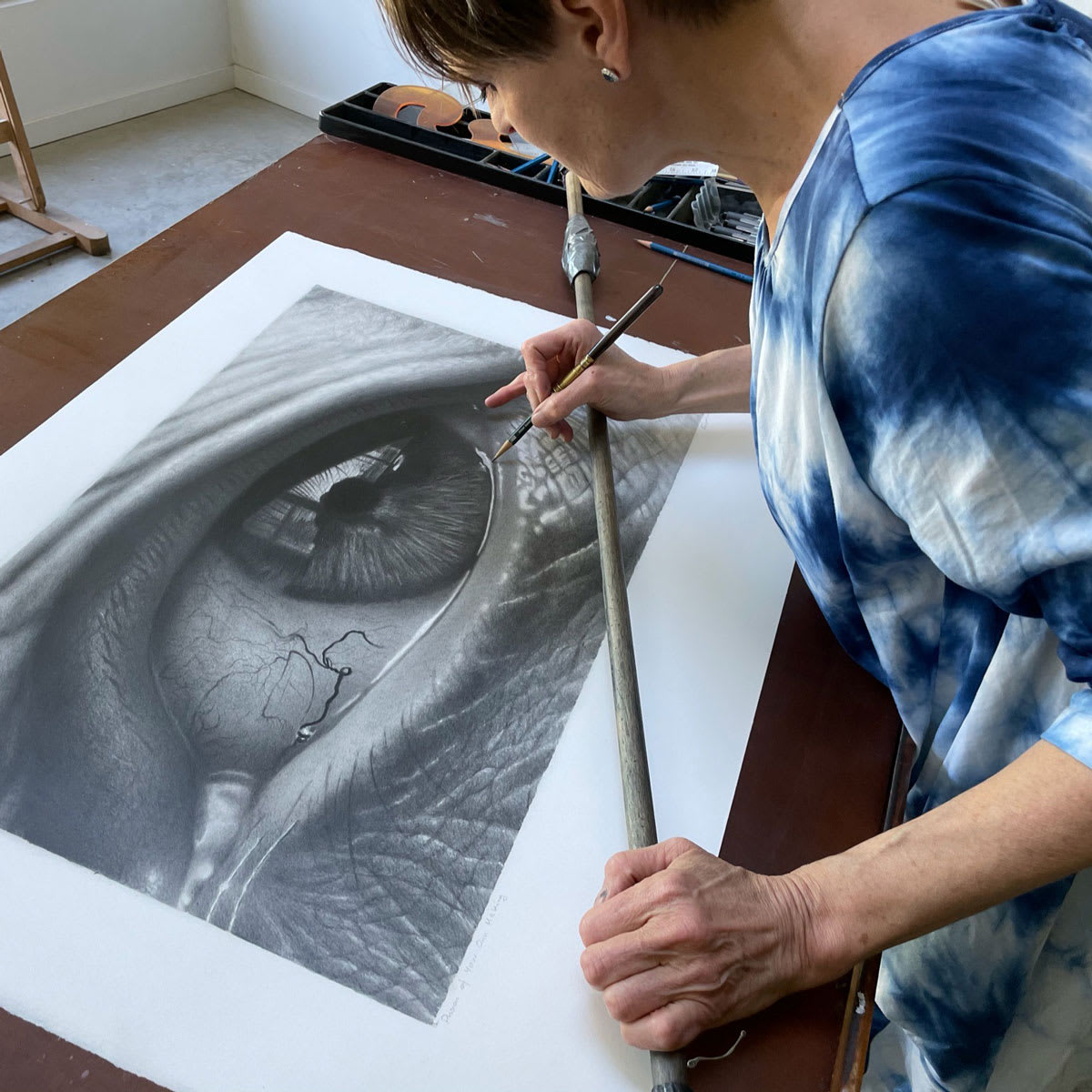 Tour des Arts - Une artiste travaille sur un dessin au fusain très détaillé d'un œil humain