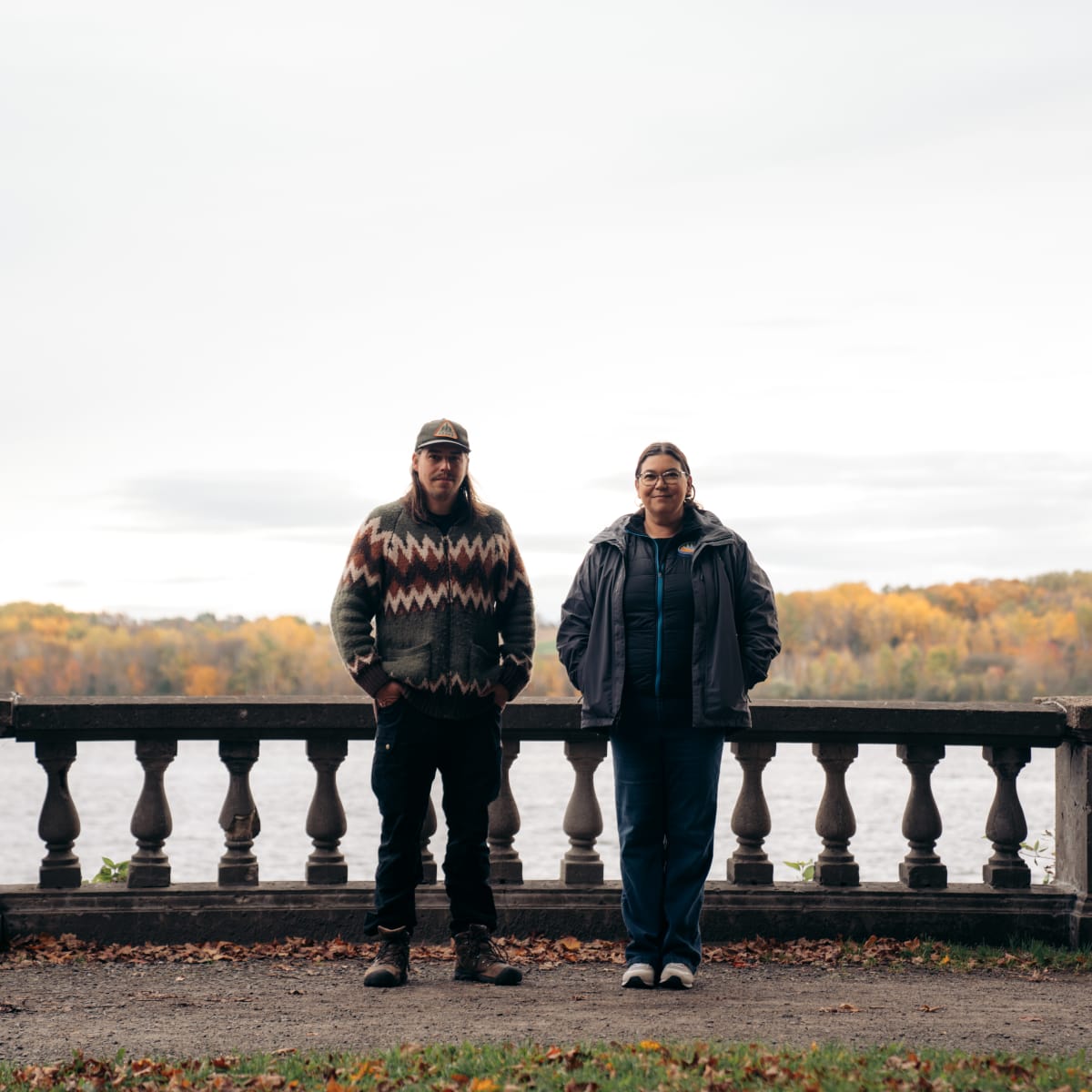 Deux personnes autochtones devant un lac en automne.