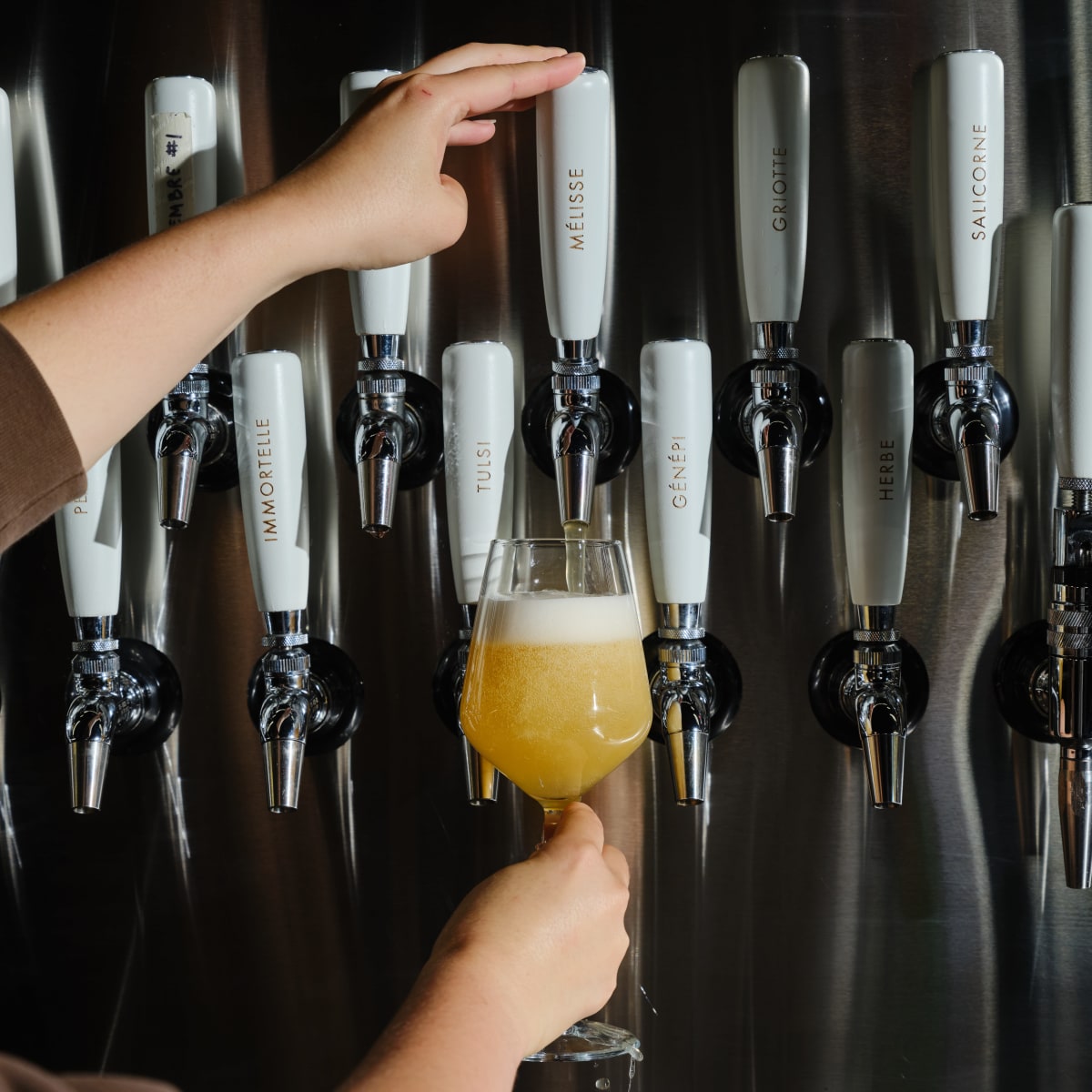 A person pouring a glass of draft beer.