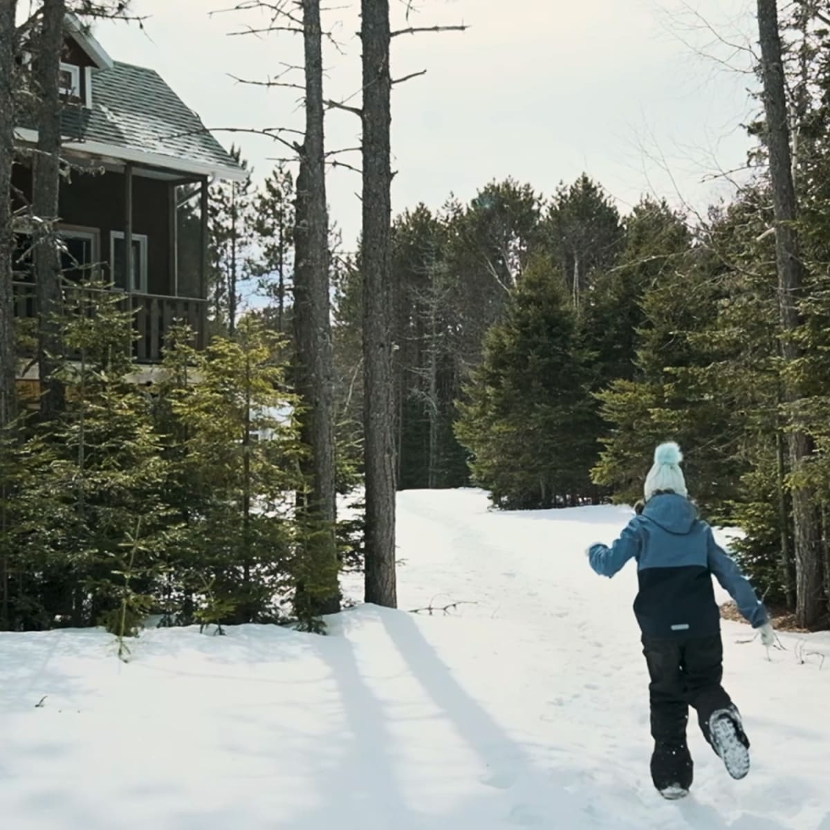 Enfant qui cours vers un chalet l'hiver.