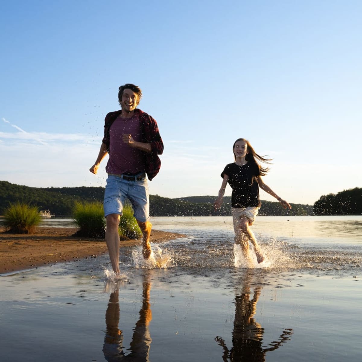 A father and daughter running on the beach.
