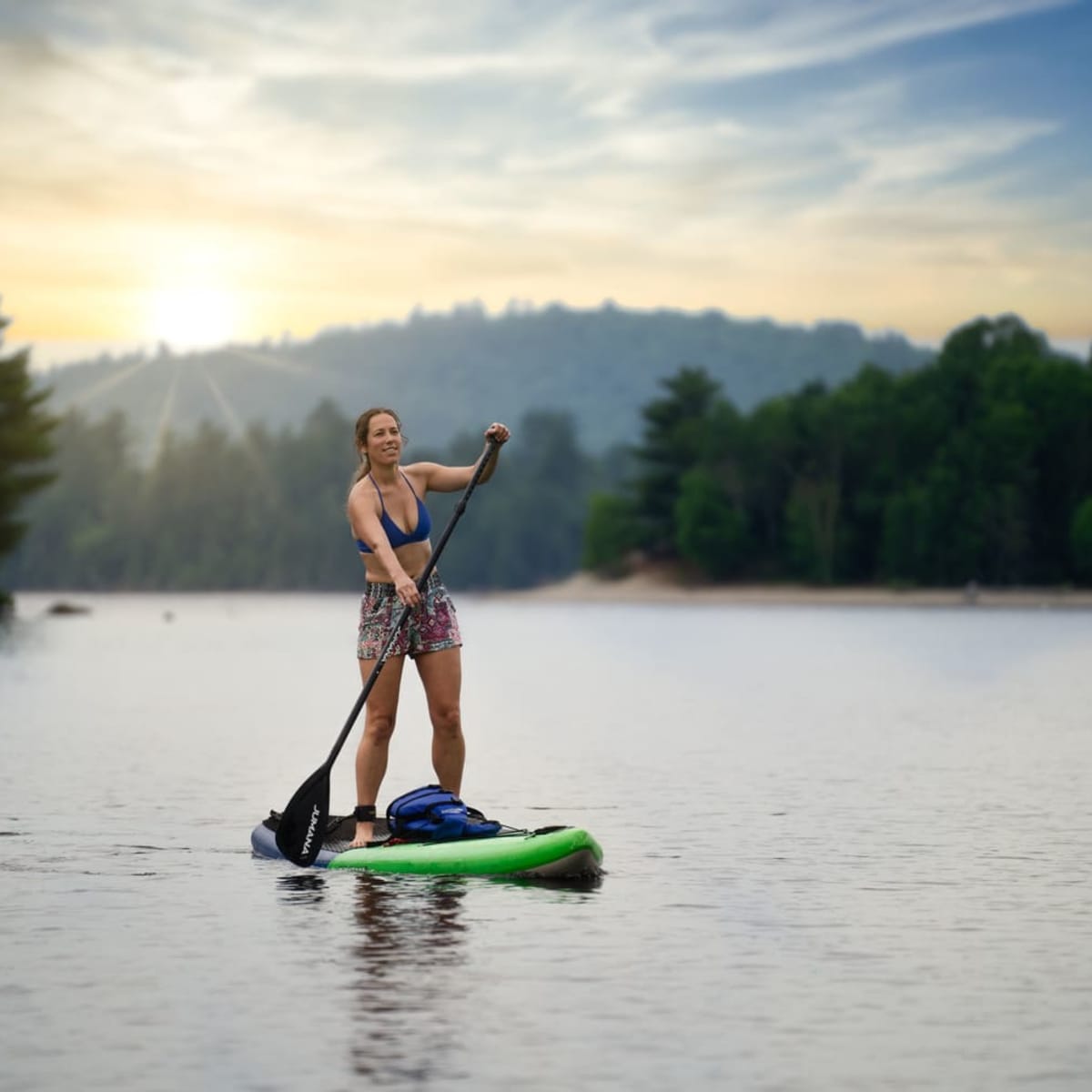 A woman paddleboarding on a lake.