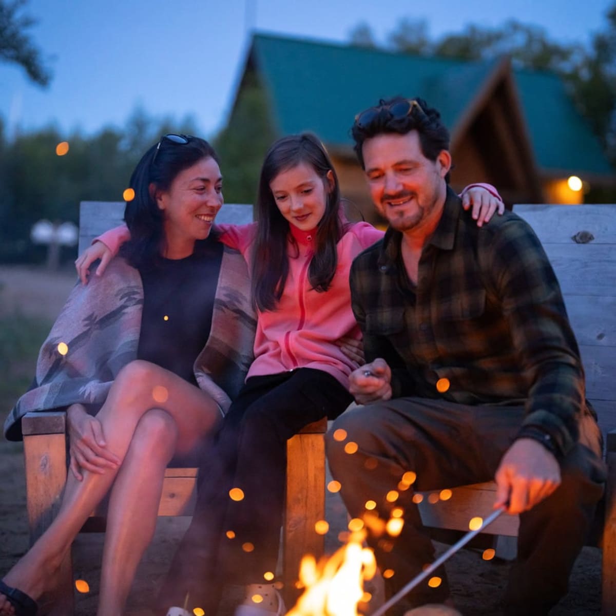A happy family gathered around a campfire in the evening.