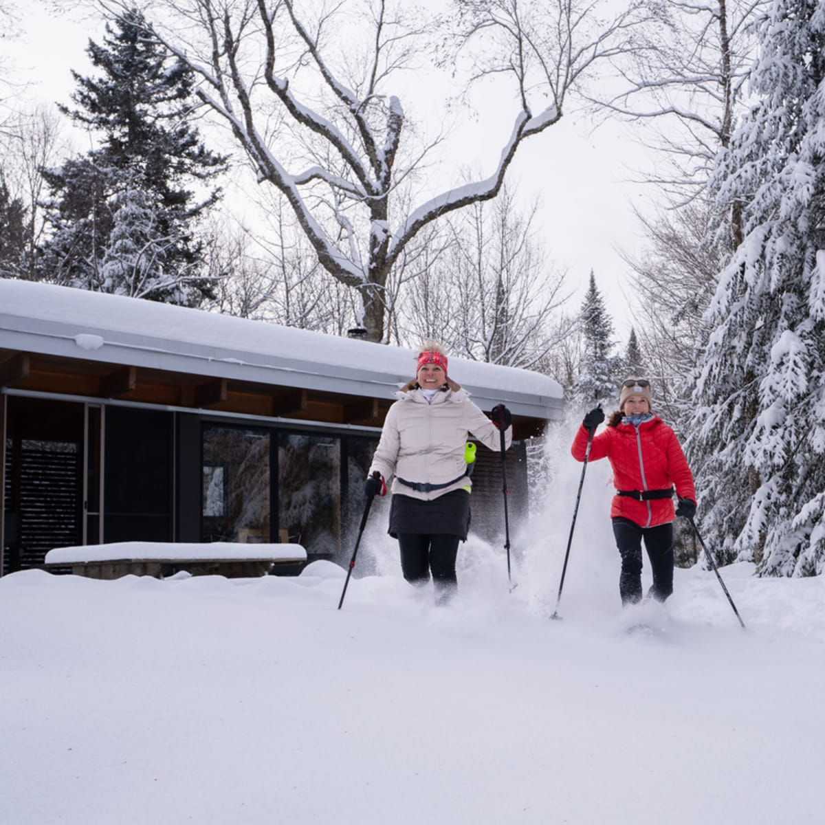 Two women snowshoeing in front of a chalet.