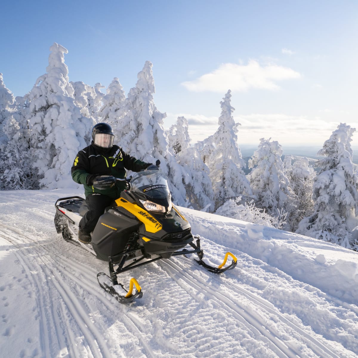 Snowmobiler on a snow-covered trail on a mountainside.