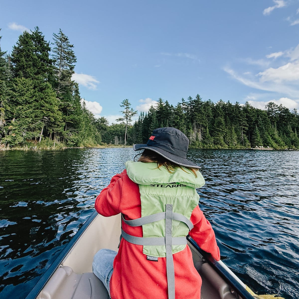 Personne assise à l'avant d'un canot sur un lac à Huttopia Les Deux Lacs - Laurentides