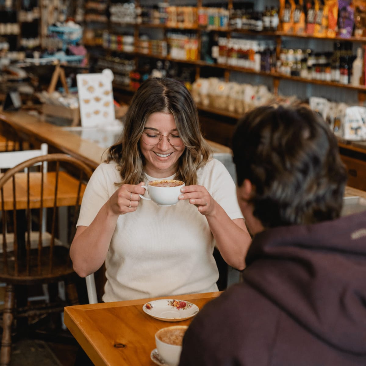 Couple assis à une table du café Aux cinq sœurs; la femme a une tasse à la main.