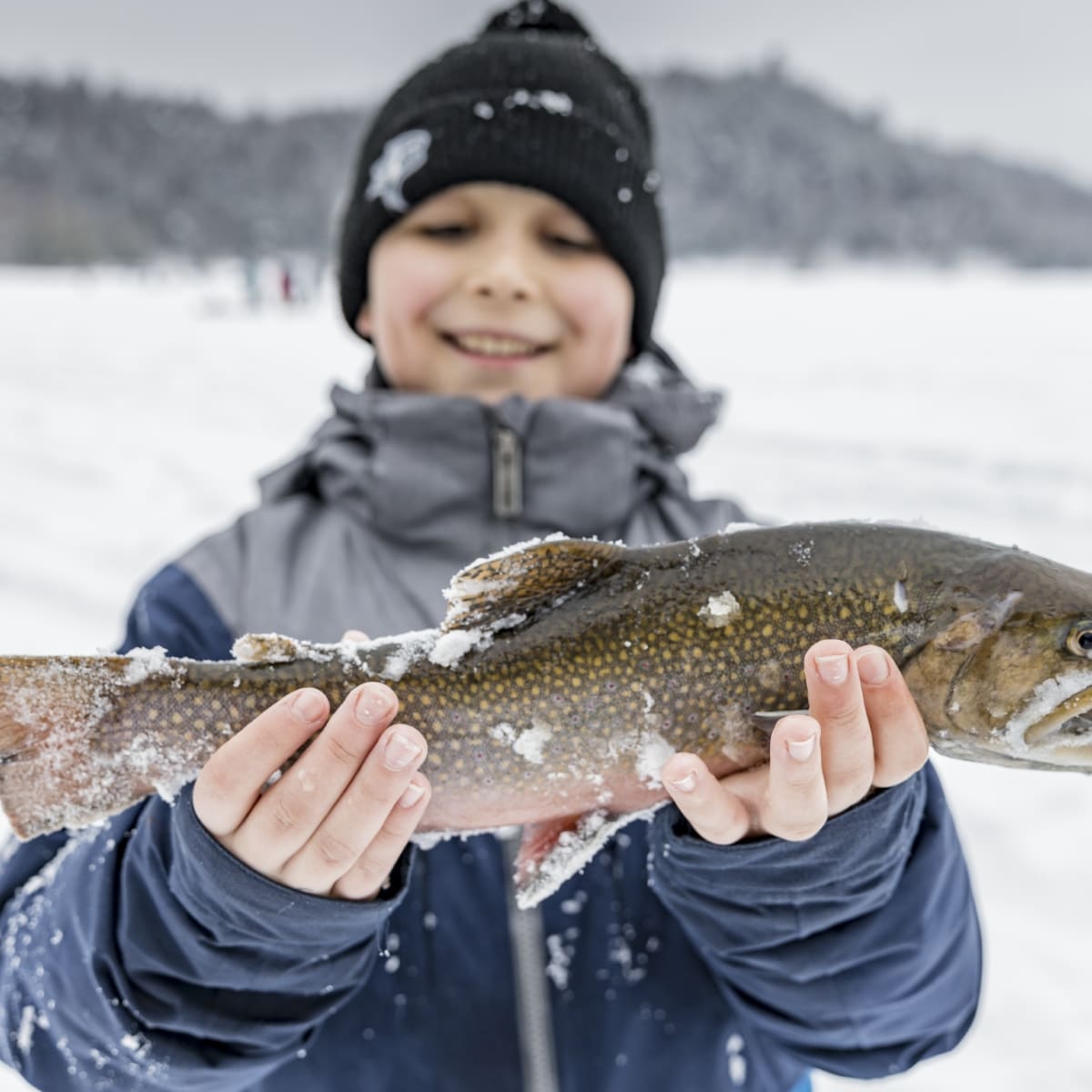 Garçon tenant un poisson et pêche blanche au Lac-Simon. 