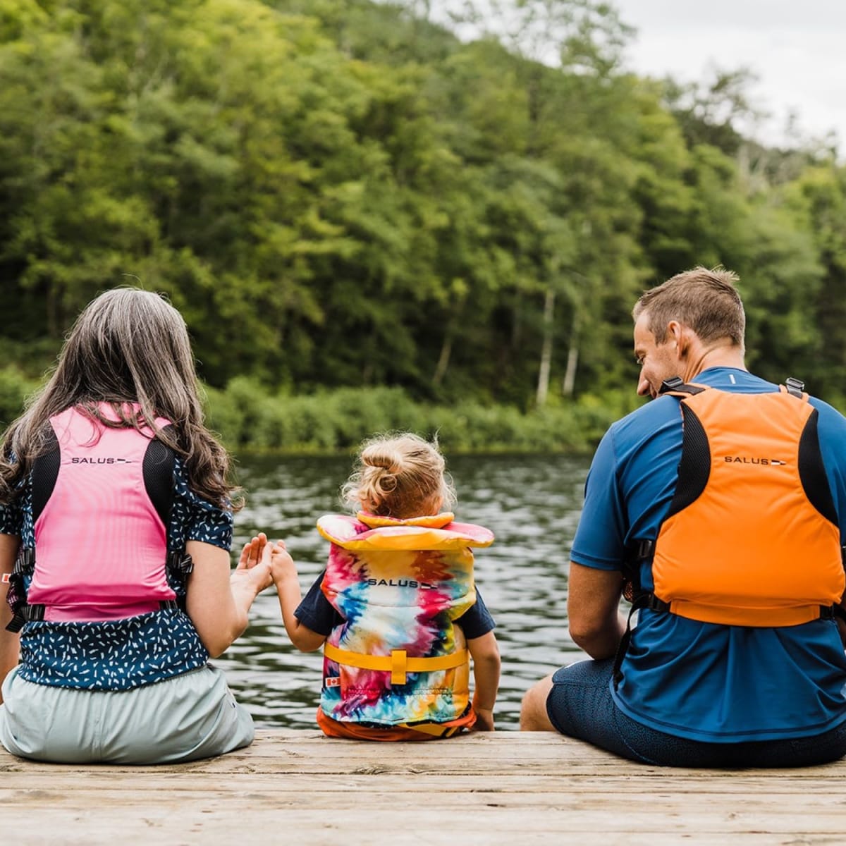 A family sitting on a pier in the summer.