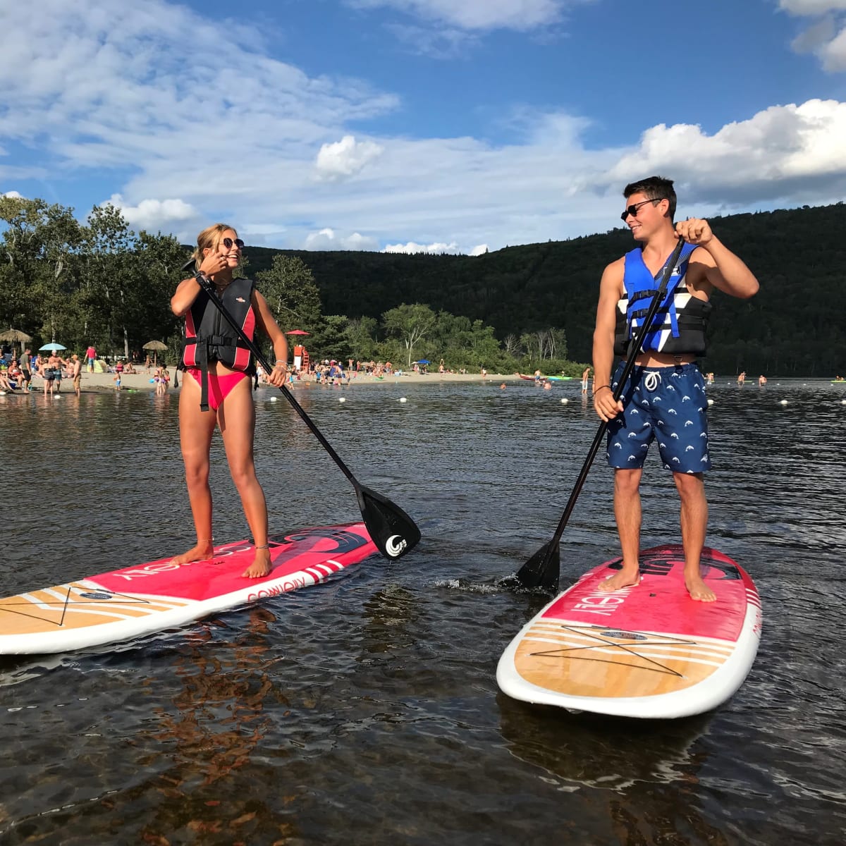A young woman and a young man paddleboarding on a lake.