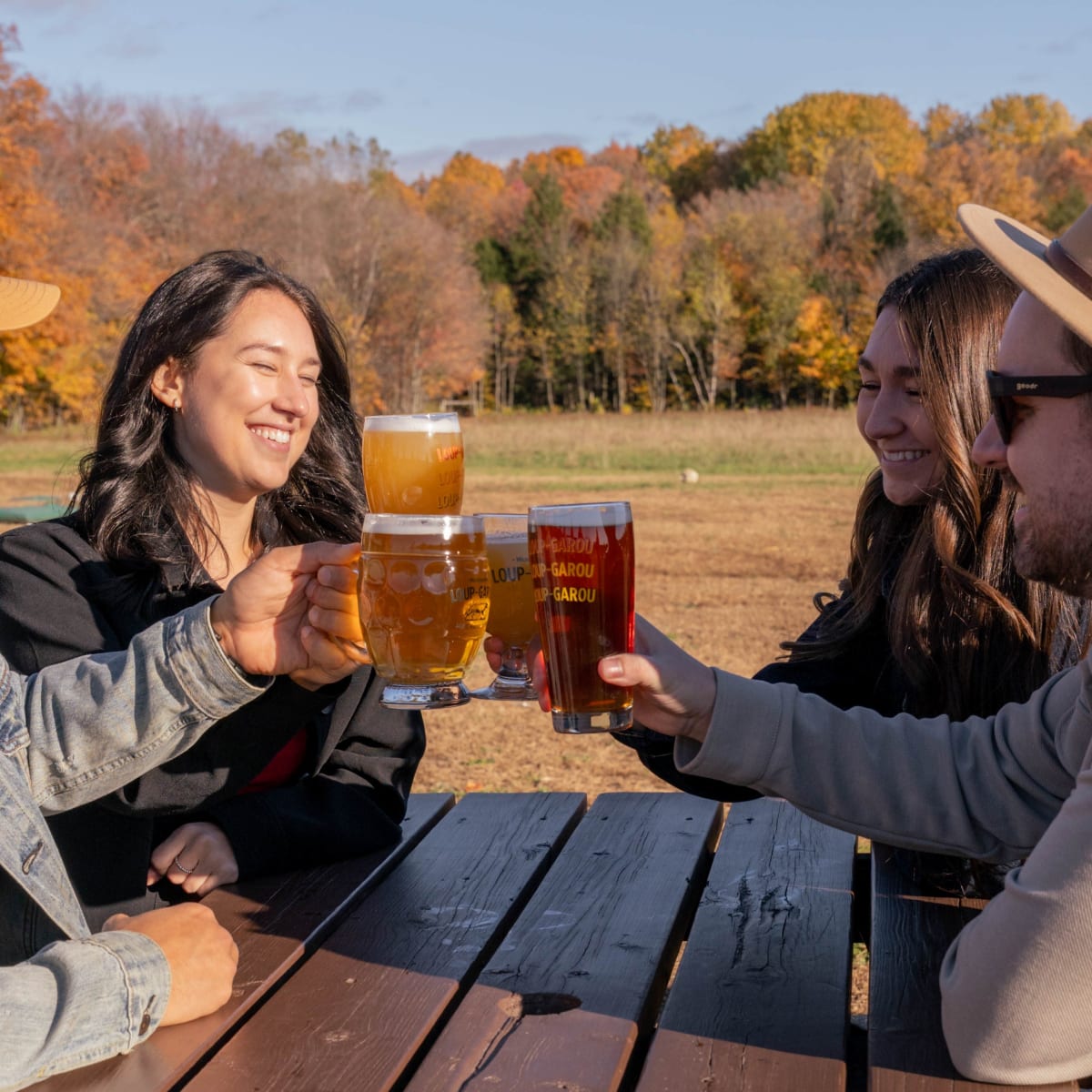 Toasting with friends over beers at an outdoor table in the fall.