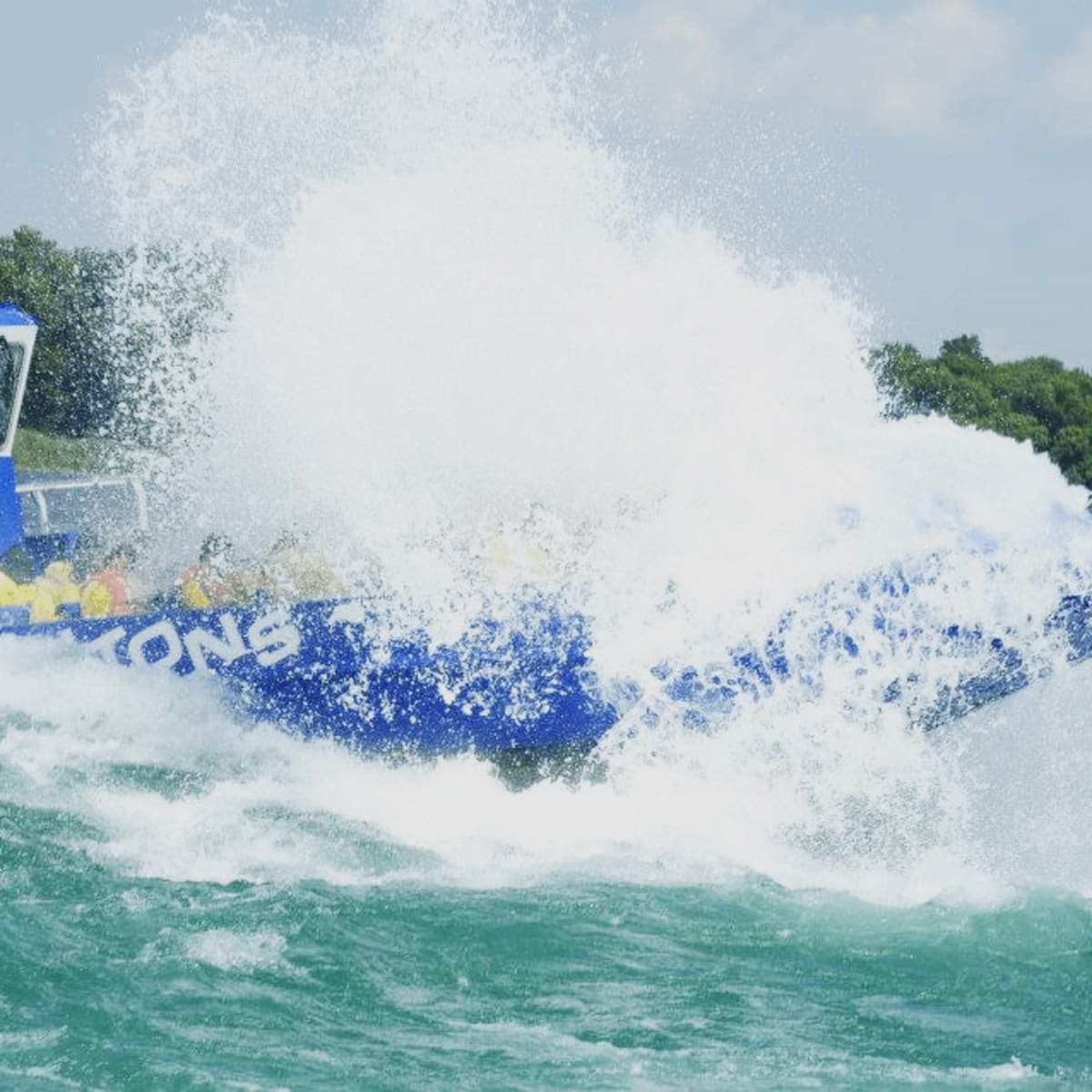 Bateau bleu Saute-Moutons entouré d'éclaboussure alors qu'il traverse une vague.