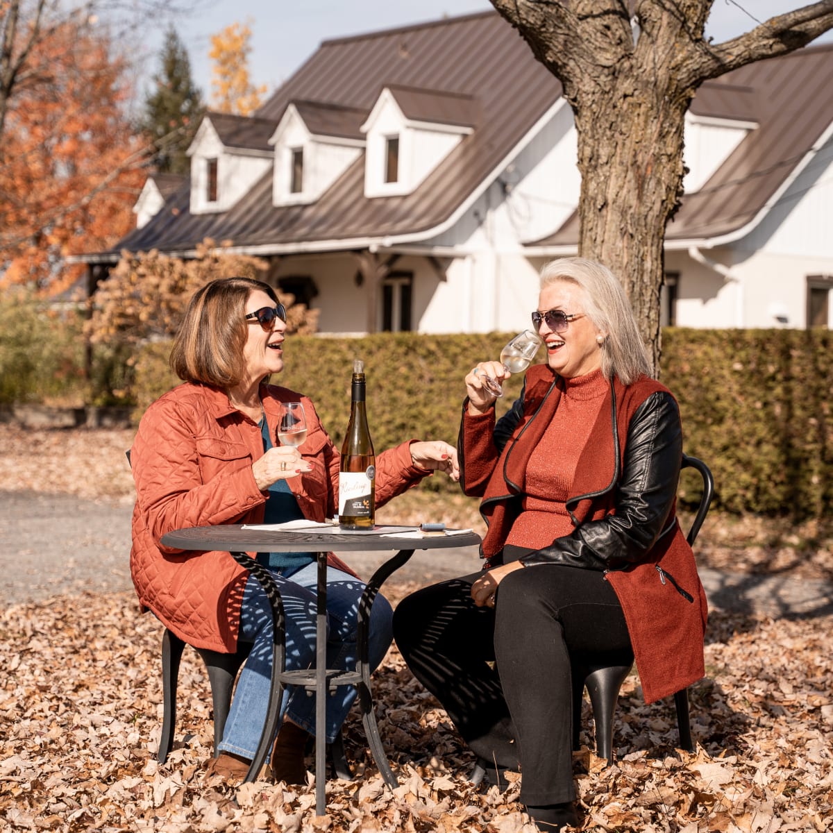 Two older women enjoying wine in the fall.