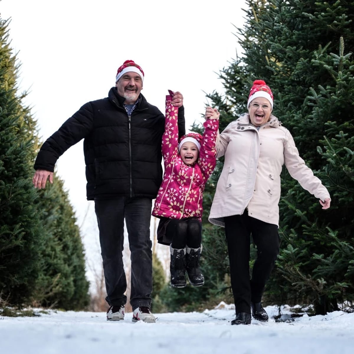 A family walks beside Christmas trees at the Village de Noël - Sapins Goupil.