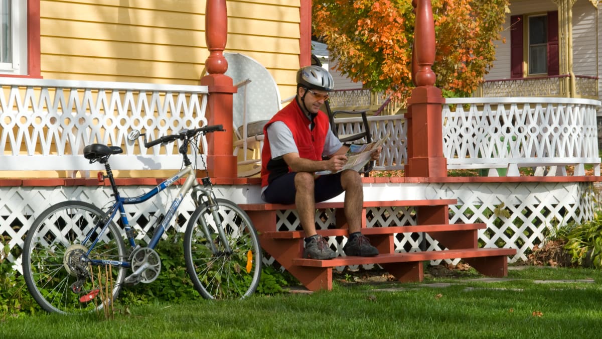 Homme assis sur un escalier en automne, son vélo à côté de lui
