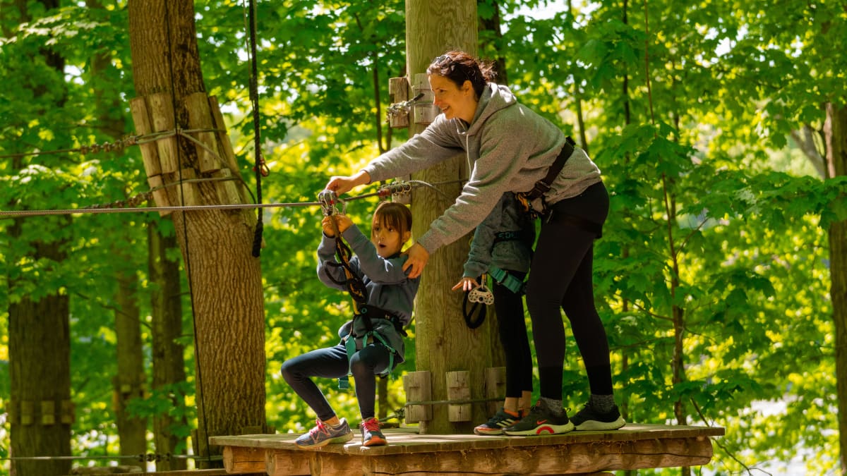 Mère et fille qui font un parcours dans les arbres à Extéria