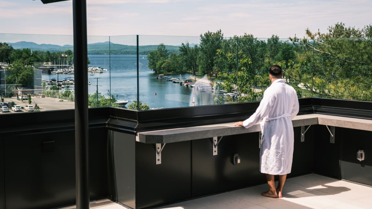 Man in a bathrobe on a balcony looking at the lake.