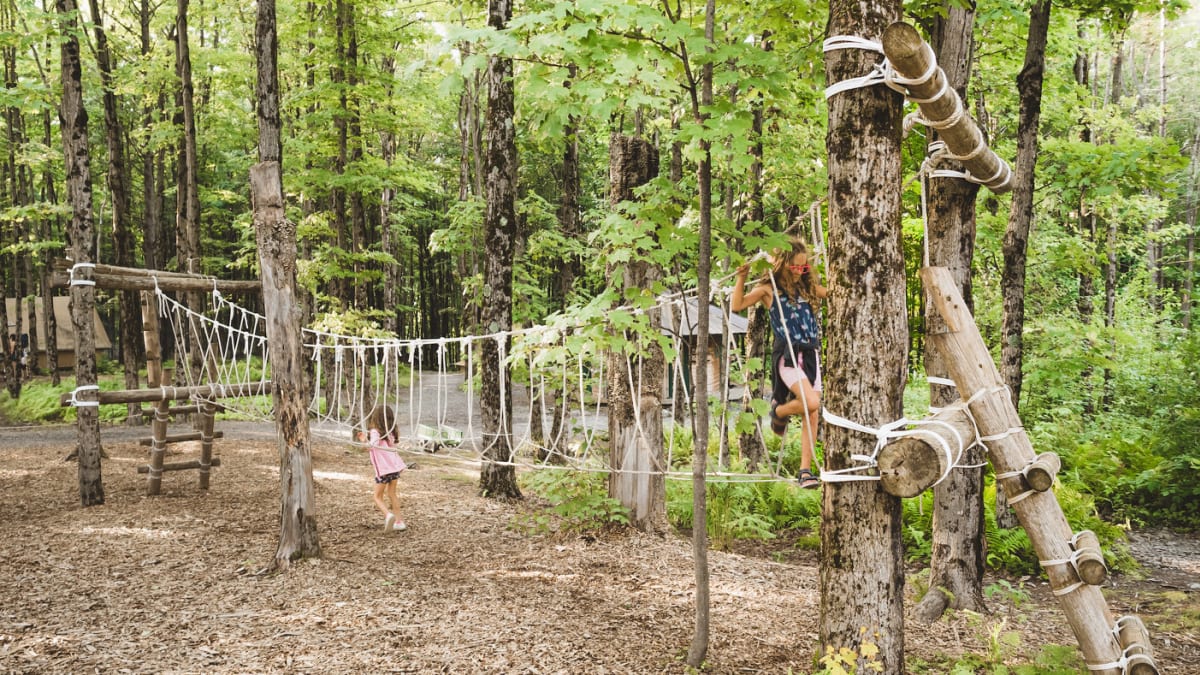 Kids on an obstacle course in the woods at Huttopia Sutton.